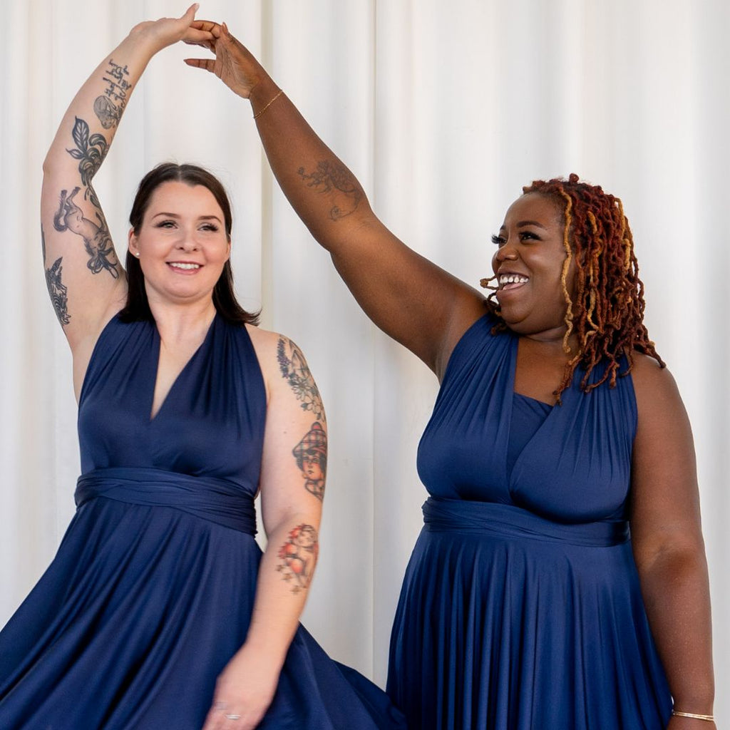 Two women wearing Henkaa Sakura navy blue dresses twirling each other