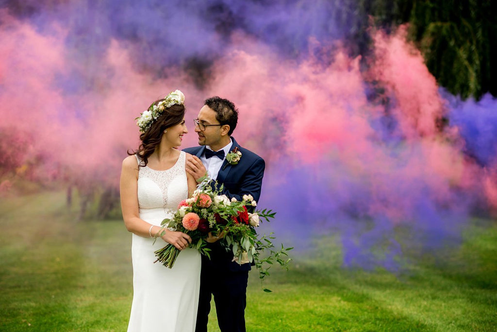 Henkaa A Bride's Story: Diana & Jas. Bride and groom embrace in front of pink and purple smoke bomb. 