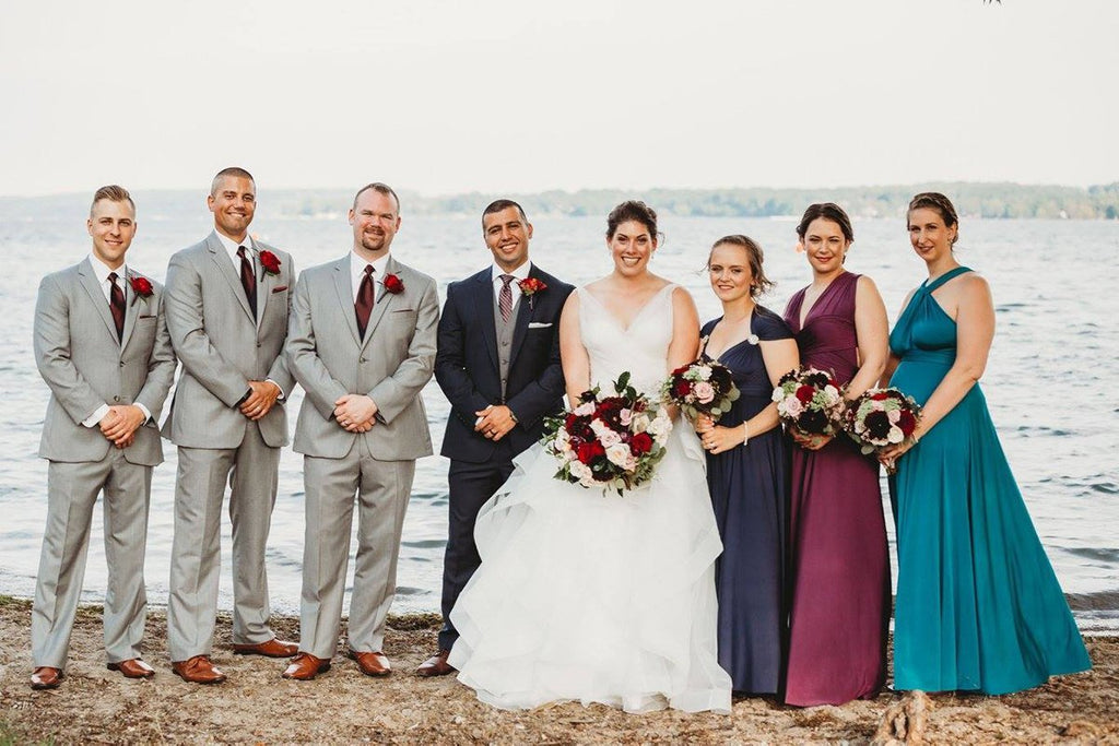 Jacqueline Sbeyti and Ayad Sbeyti pose with the wedding pary at the water front. bridesmaids are wearing Henkaa Sakura Maxi Convertible Dresses in Navy Blue, Plum Purple and Turquoise Teal.