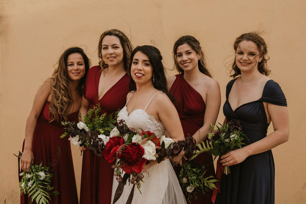 A bride and her bridesmaids and best woman smile for a photo in Portugal wearing Henkaa Sakura Convertible Dresses in Burgundy Wine and Navy Blue