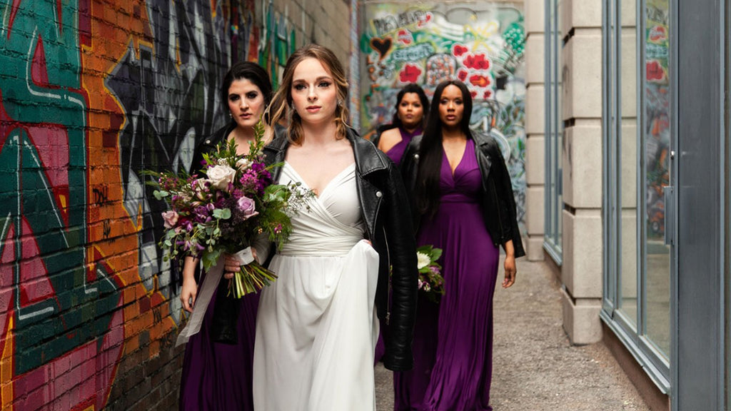 Henkaa  bride wearing the Iris Chiffon Convertible Wedding Dress and bridal party in Henkaa plum purple convertible dresses shot in a graffiti alley. 