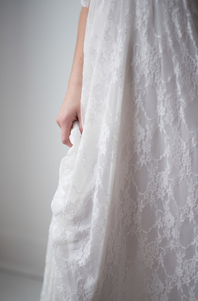 A photograph of a person wearing a Hana Lace Maxi Overlay Skirt in Pure Ivory
