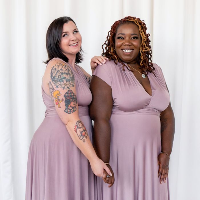 Two models clasping hands and wearing Henkaa Sakura Maxi convertible dresses in Mauve Taupe