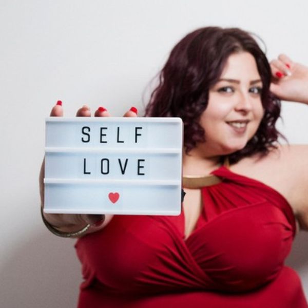 Model in Henkaa Sakura Red Dress holding SELF LOVE sign