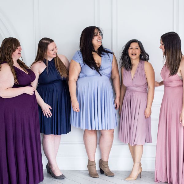 5 women standing and laughing wearing Henkaa convertible infinity dresses